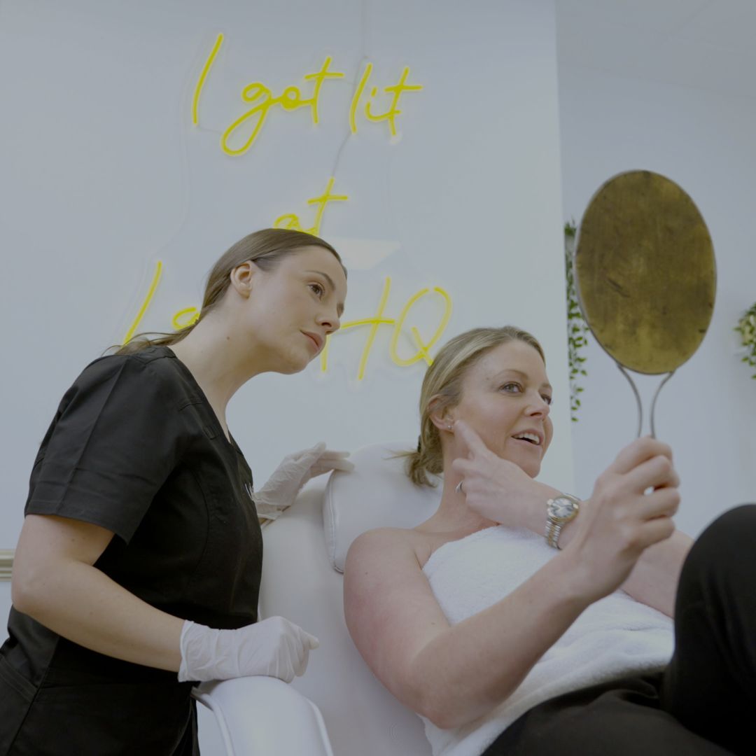 client & therapist looking at the skin through a handheld mirror
