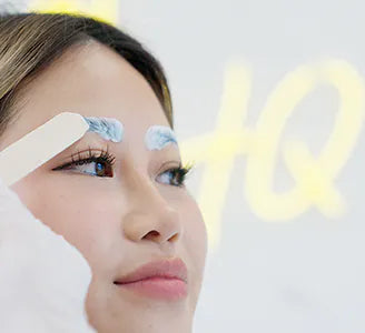 woman having numbing cream applied to her eyebrows